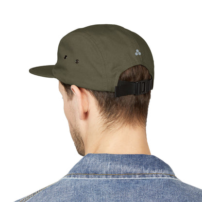 Person wearing a green cap with a brand logo on a white background. Clean modern holiday tree symbol designed for embroidery. TEEZOCA