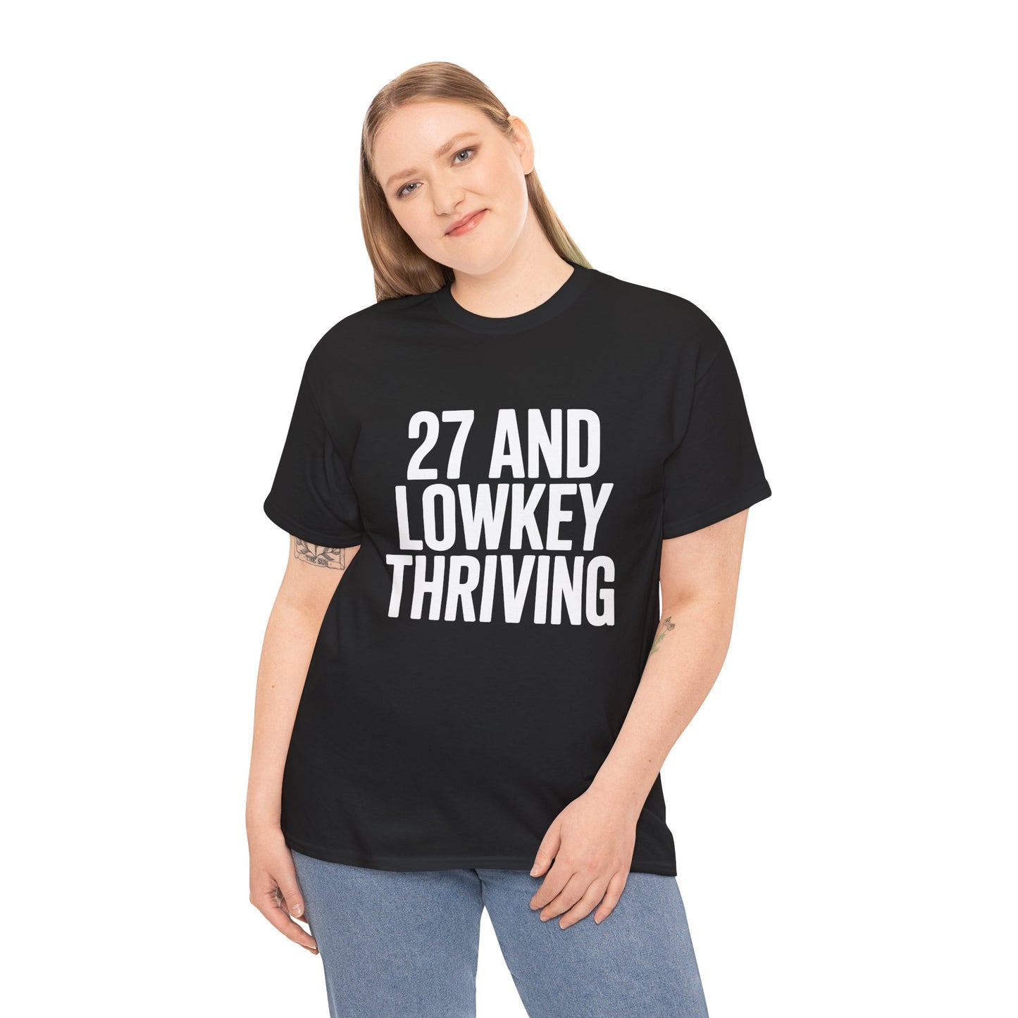 Person wearing a black t-shirt with '27 AND LOWKEY THRIVING' text on a white background