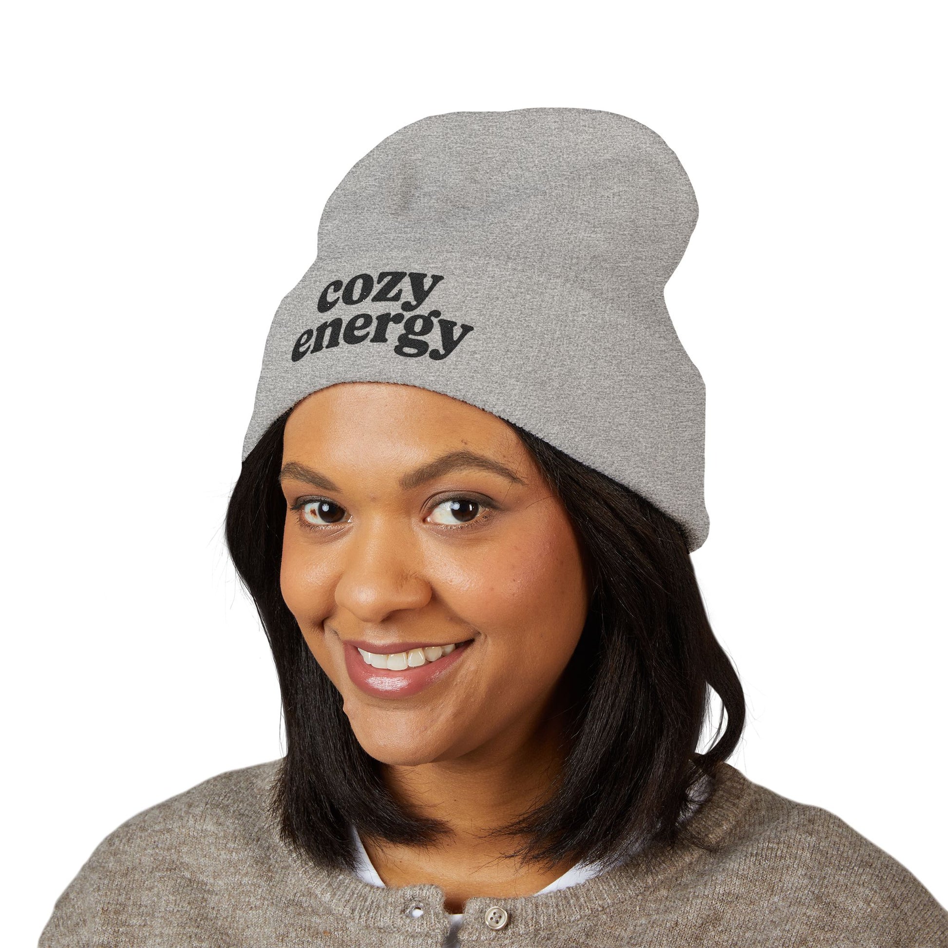 Person wearing a gray beanie with 'cozy energy' text on a white background