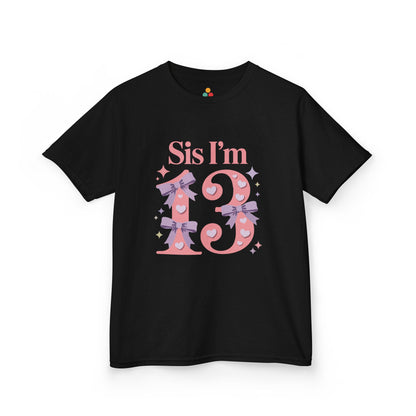Black t‑shirt with pink “Sis I’m 13” design featuring hearts, lilac bows, and sparkles, flat front view.