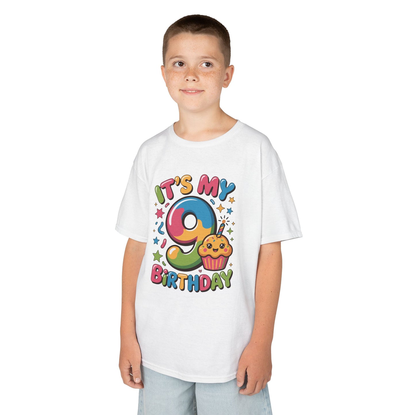 “Boy Model ‘It’s My 9th Birthday’ shirt with rainbow 9 and smiling cupcake, confetti and stars, kids unisex tee, flat display.”

