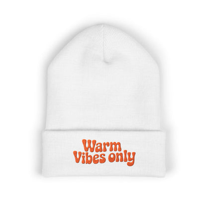 White beanie with 'Warm Vibes only' text in orange on a white background. Close-up of cheerful orange “Warm vibes only” embroidery on winter knit hat.