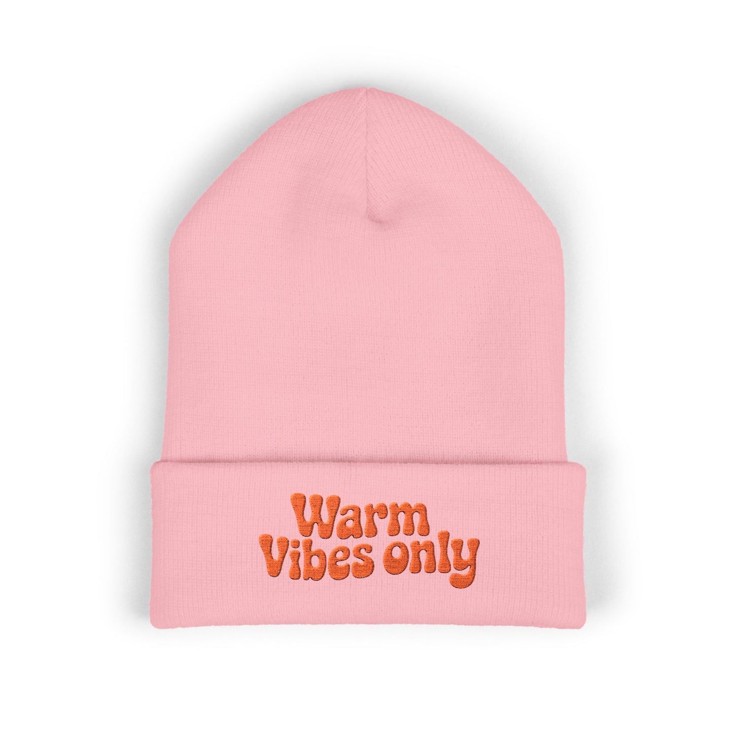 Pink beanie with 'Warm Vibes only' text on a white background. Close-up of cheerful orange “Warm vibes only” embroidery on winter knit hat.