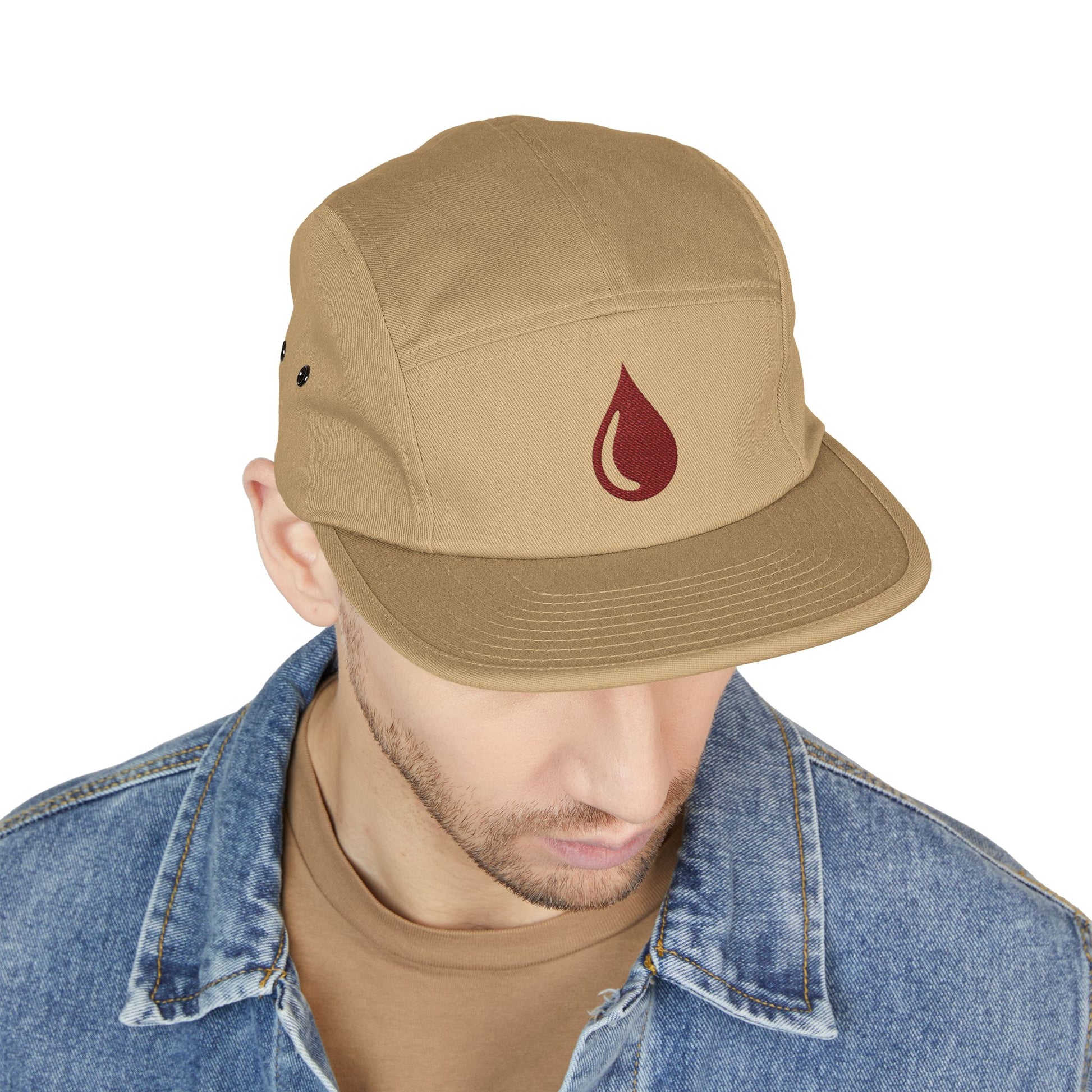 Man wearing a tan cap with a red logo on a white background. Minimal coffee drop icon embroidered in a clean, modern style 5-panel cap. TEEZOCA