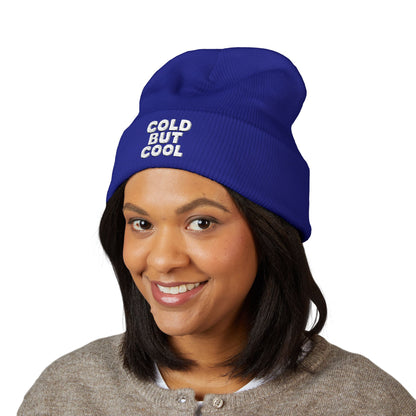Person wearing a blue beanie with 'COLD BUT COOL' text on a white background
