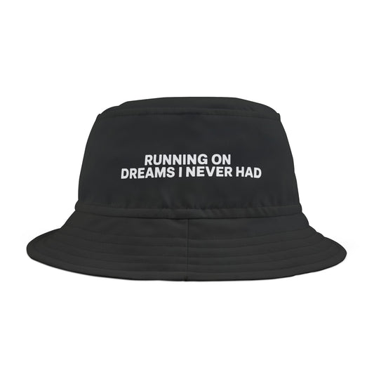 Funny black bucket hat with white text 'RUNNING ON DREAMS I NEVER HAD' on a white background. TEEZOCA