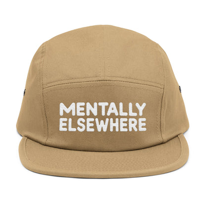 Beige cap with 'MENTALLY ELSEWHERE' text on a white background. Mentally Elsewhere embroidered text design on five-panel cap. TEEZOCA