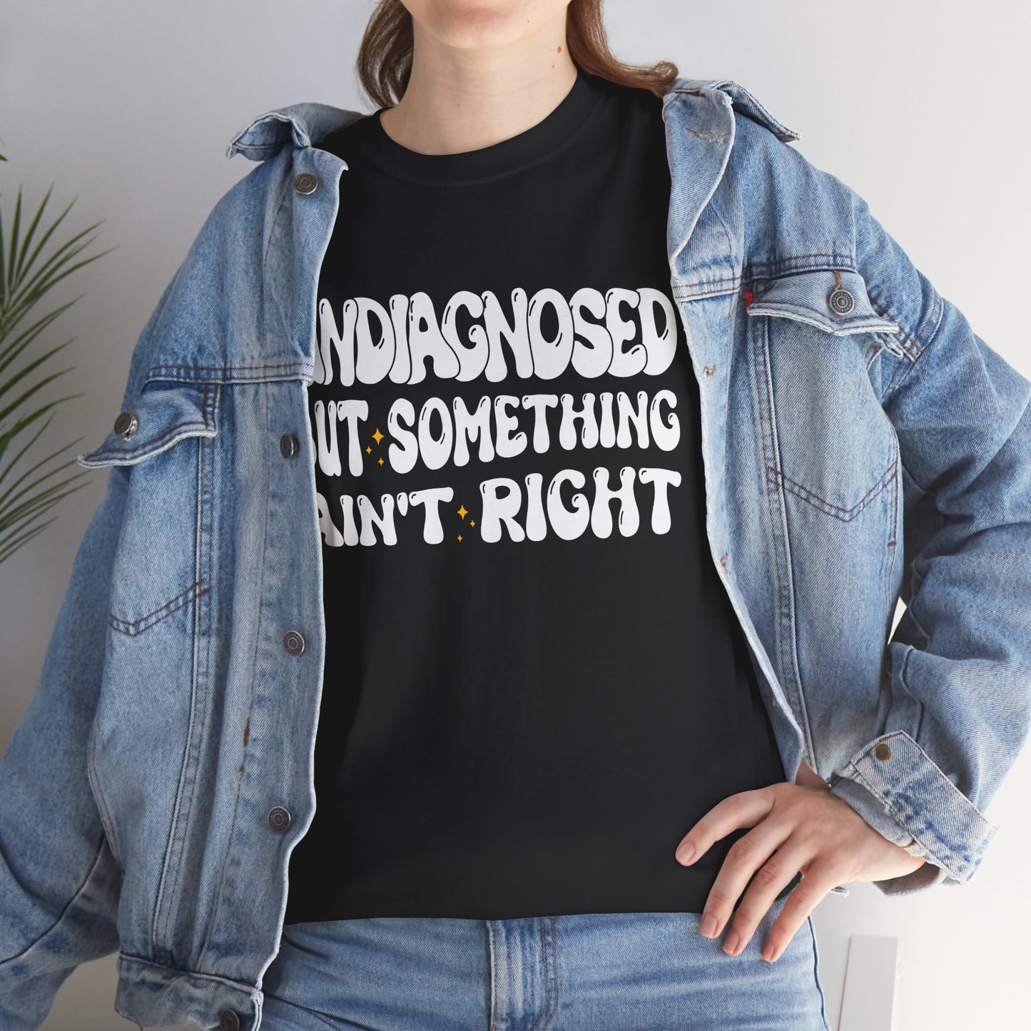 “Female model wearing Teezoca Undiagnosed But Something Ain’t Right t-shirt, bold white groovy lettering, dark navy tee, front.”​

