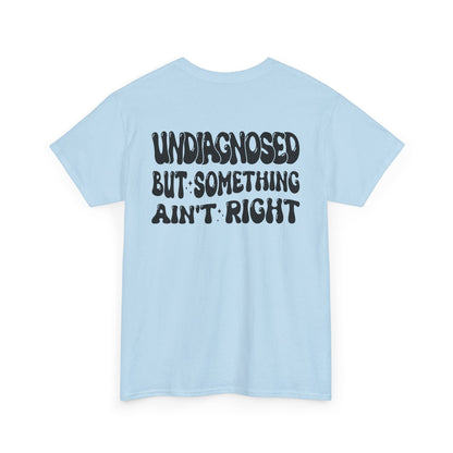 Back Print of a Light Blue T-shirt featuring the viral meme phrase "Undiagnosed But Something Ain't Right" in bold wavy retro typography, a trending funny mental health meme shirt, unhinged humor tee, therapy meme graphic, and relatable back print statement design.
