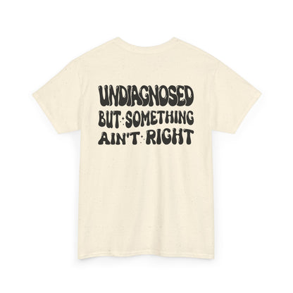 Back Print of a Natural T-shirt featuring the viral meme phrase "Undiagnosed But Something Ain't Right" in bold wavy retro typography, a trending funny mental health meme shirt, unhinged humor tee, therapy meme graphic, and relatable back print statement design.
