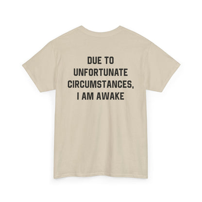 Back Print of a Sand T-shirt featuring bold black text reading "Due To Unfortunate Circumstances, I Am Awake," funny back print sarcastic quote shirt, not a morning person tee, dry humor graphic shirt, and blunt statement design.
