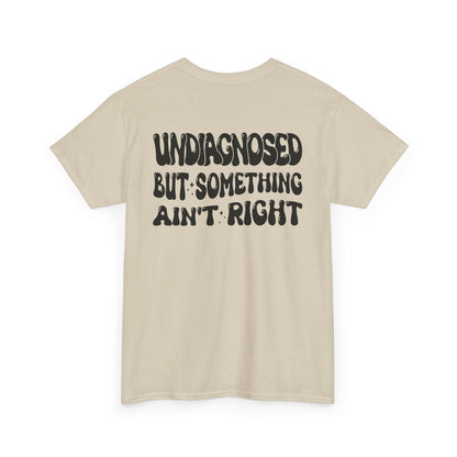 Back Print of a Sand T-shirt featuring the viral meme phrase "Undiagnosed But Something Ain't Right" in bold wavy retro typography, a trending funny mental health meme shirt, unhinged humor tee, therapy meme graphic, and relatable back print statement design.

