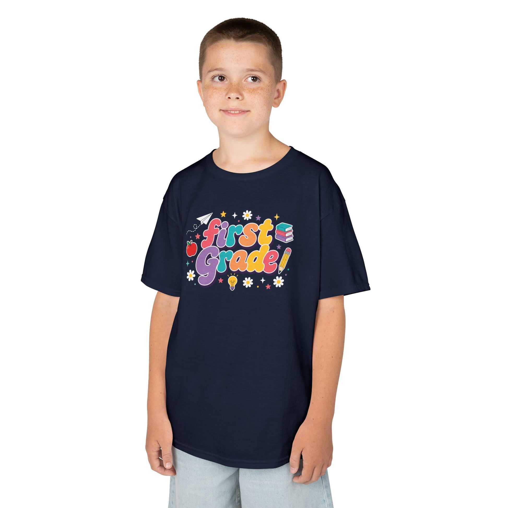 Child wearing a navy t-shirt with 'First Grade' text on a white background. TEEZOCA t-shirt with bright classroom doodles for a First Day of First Grade Shirt photo moment.