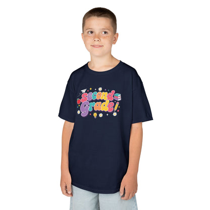 Child wearing a navy t-shirt with 'Second Grade!' text on a white background. TEEZOCA t-shirt with a cute classroom graphic for a 2nd grade shirt for boys or a 2nd grade shirt for girls.