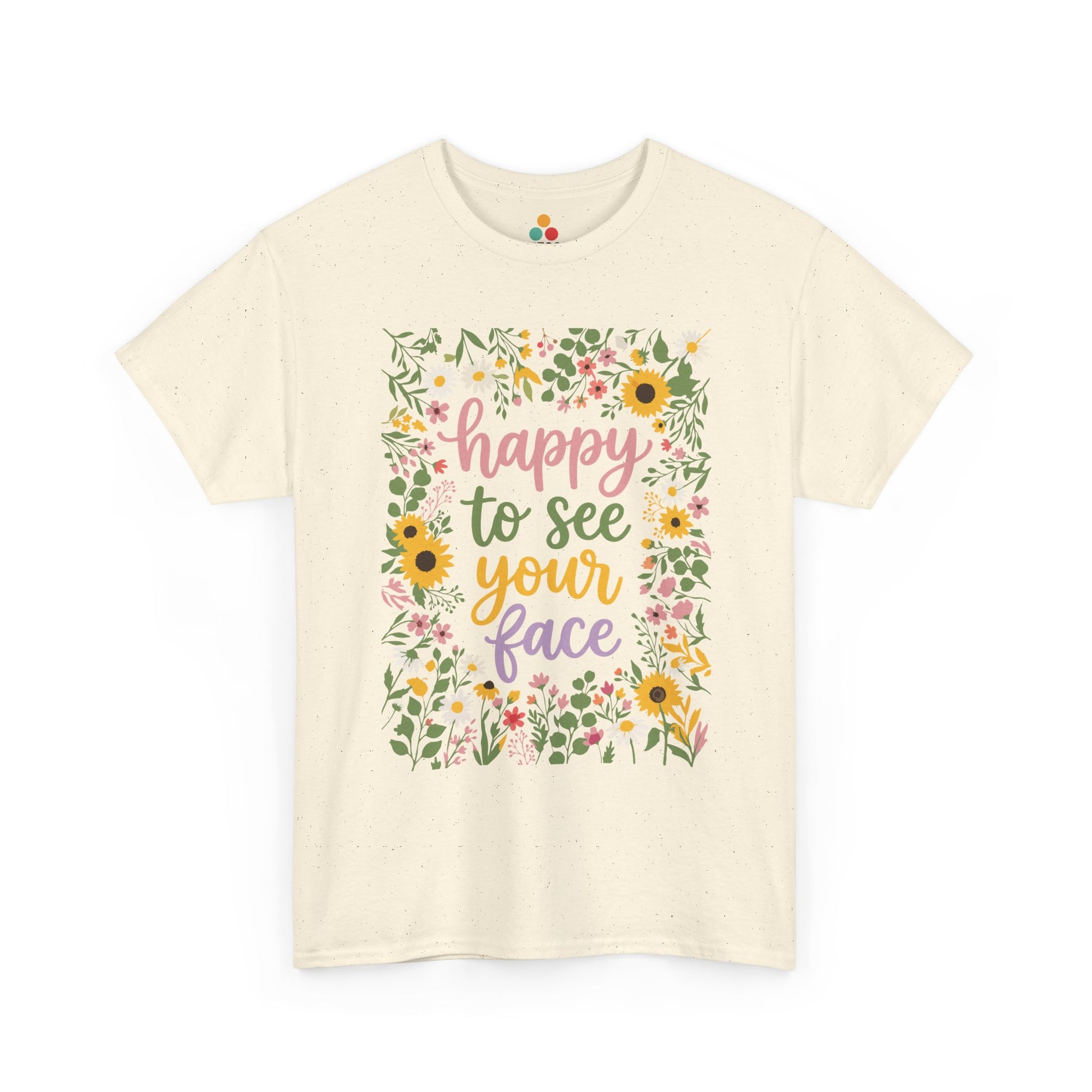 Close-up of a Beige T-shirt featuring the phrase “Happy to See Your Face” in pastel lettering framed by a floral border with sunflowers and wildflowers.

