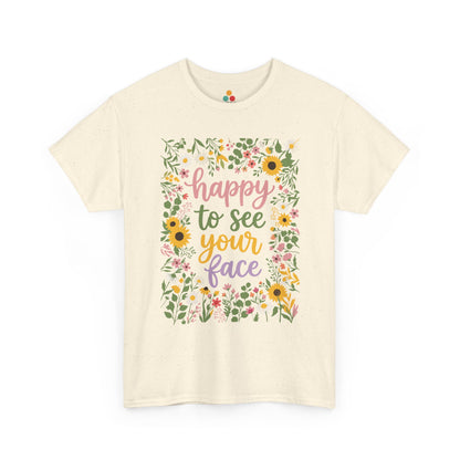 Close-up of a Beige T-shirt featuring the phrase “Happy to See Your Face” in pastel lettering framed by a floral border with sunflowers and wildflowers.

