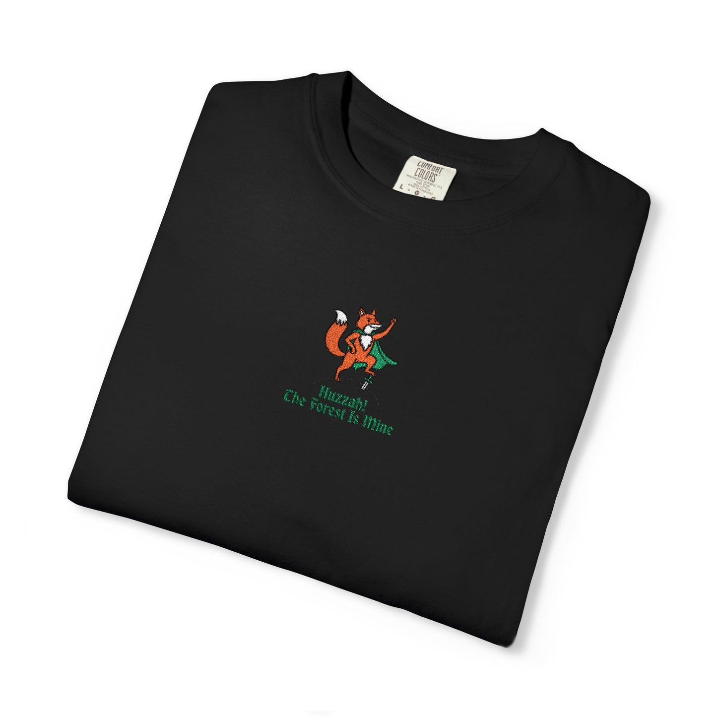 Close-up of a Comfort Colors®  
BLACK shirt featuring an embroidered orange fox in a green cape with the saying "Huzzah! The Forest Is Mine."

