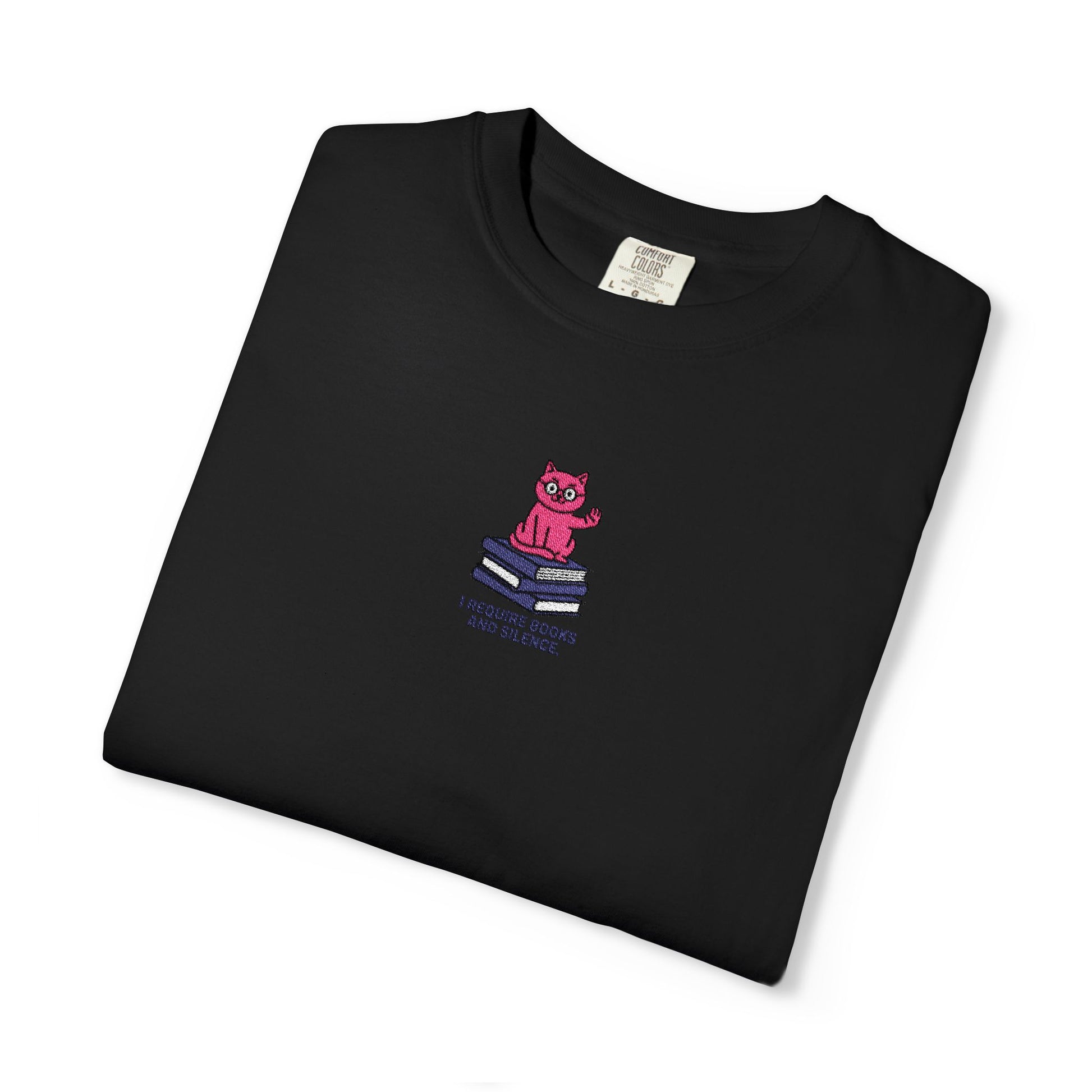   Close-up of a Comfort Colors®  Black shirt featuring an embroidered pink cat sitting on books with the saying “I Require Books and Silence.”

