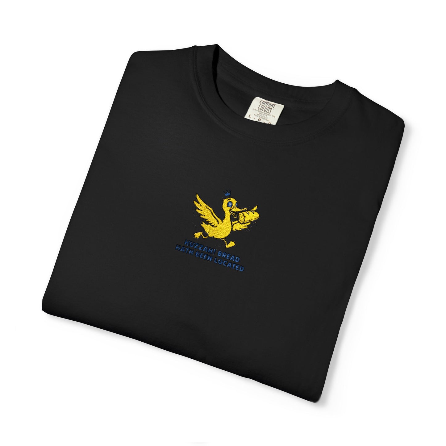 Close-up of a Comfort Colors®   Black shirt featuring an embroidered yellow duck carrying bread with the saying “Huzzah! Bread Must Be Located.”

