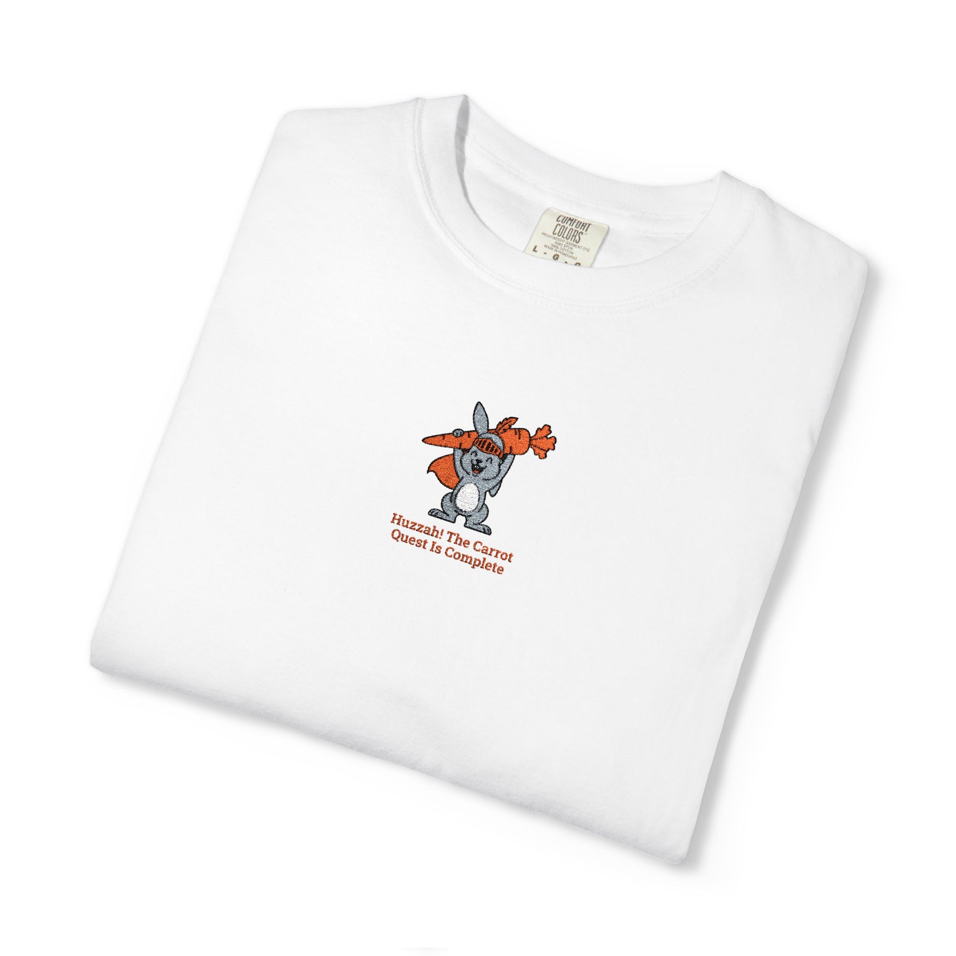 Close-up of a Comfort Colors® WHITE shirt featuring a rabbit holding carrots with the saying “Huzzah! The Carrot Quest Is Complete.”

