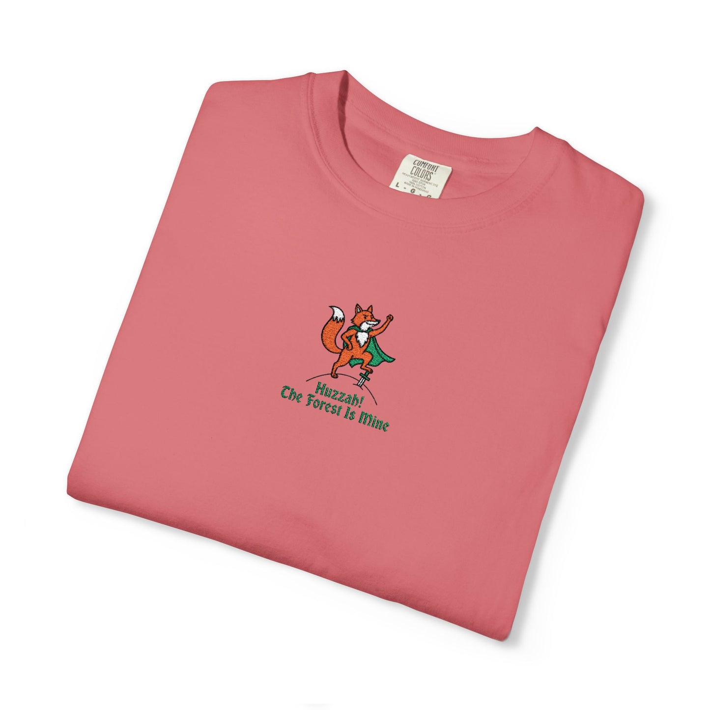Close-up of a Comfort Colors®  
Watermelon shirt featuring an embroidered orange fox in a green cape with the saying "Huzzah! The Forest Is Mine."

