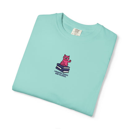  Close-up of a Comfort Colors®  chalky mint  shirt featuring an embroidered pink cat sitting on books with the saying “I Require Books and Silence.”

