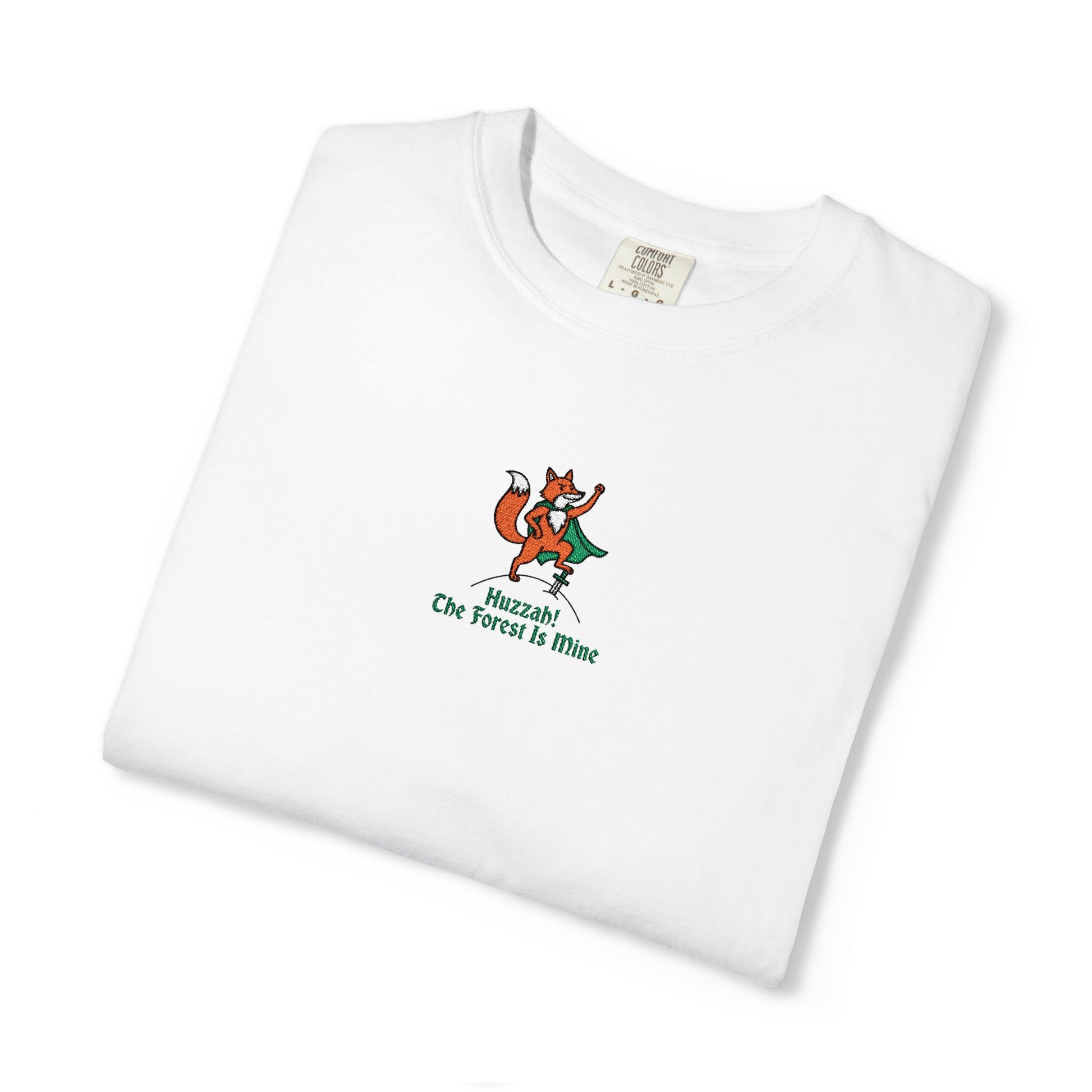 Close-up of a Comfort Colors® shirt featuring an embroidered orange fox in a green cape with the saying "Huzzah! The Forest Is Mine."


