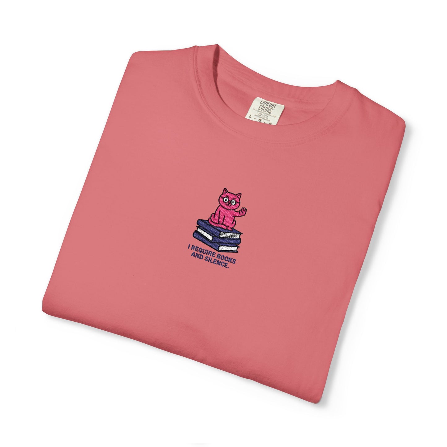   Close-up of a Comfort Colors®  watermelon shirt featuring an embroidered pink cat sitting on books with the saying “I Require Books and Silence.”

