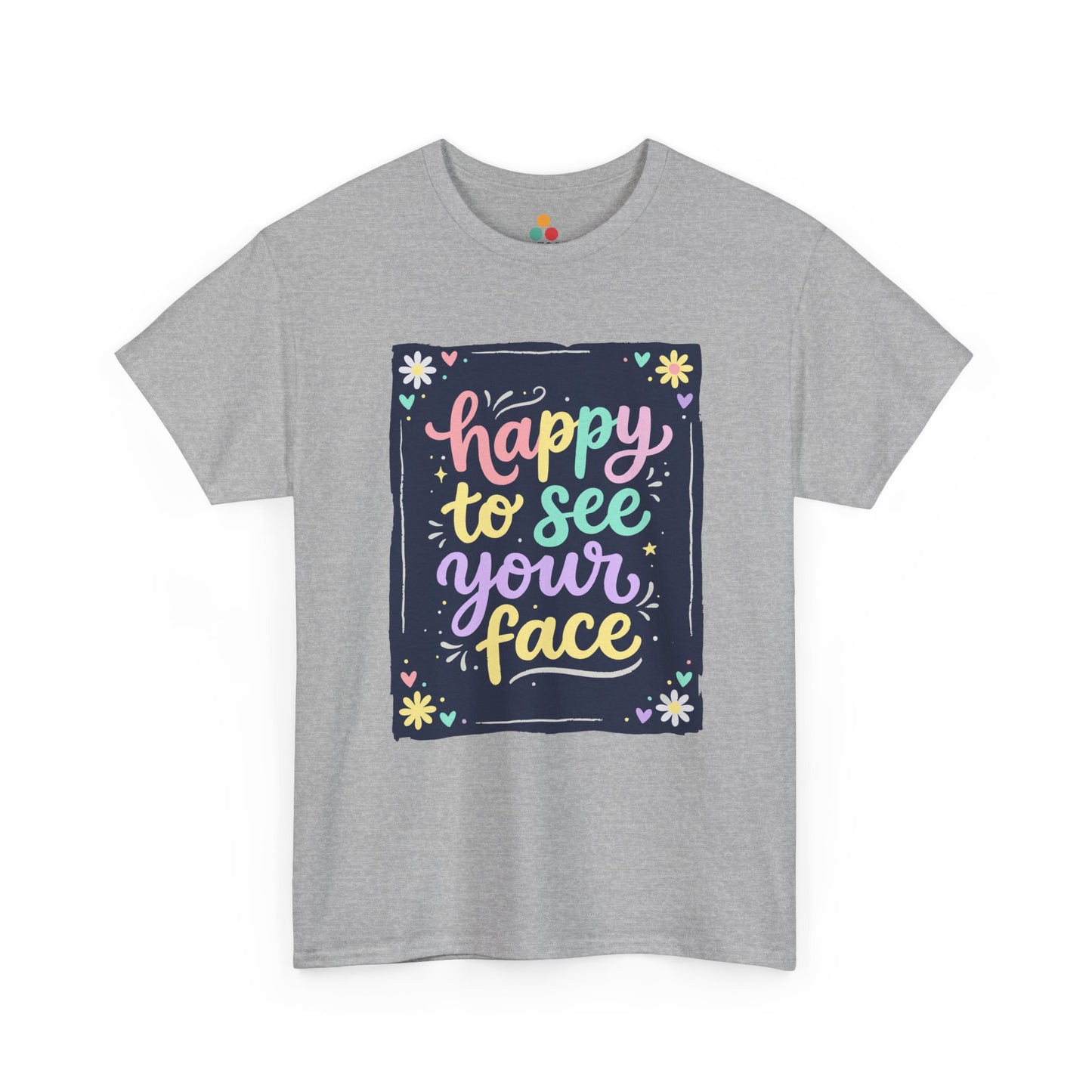 Close-up of a Gray Heather T-shirt featuring a colorful "Happy to See Your Face" hand-lettered graphic framed with flowers and hearts on a navy background panel.
