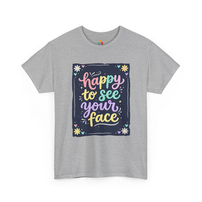 Close-up of a Gray Heather T-shirt featuring a colorful "Happy to See Your Face" hand-lettered graphic framed with flowers and hearts on a navy background panel.
