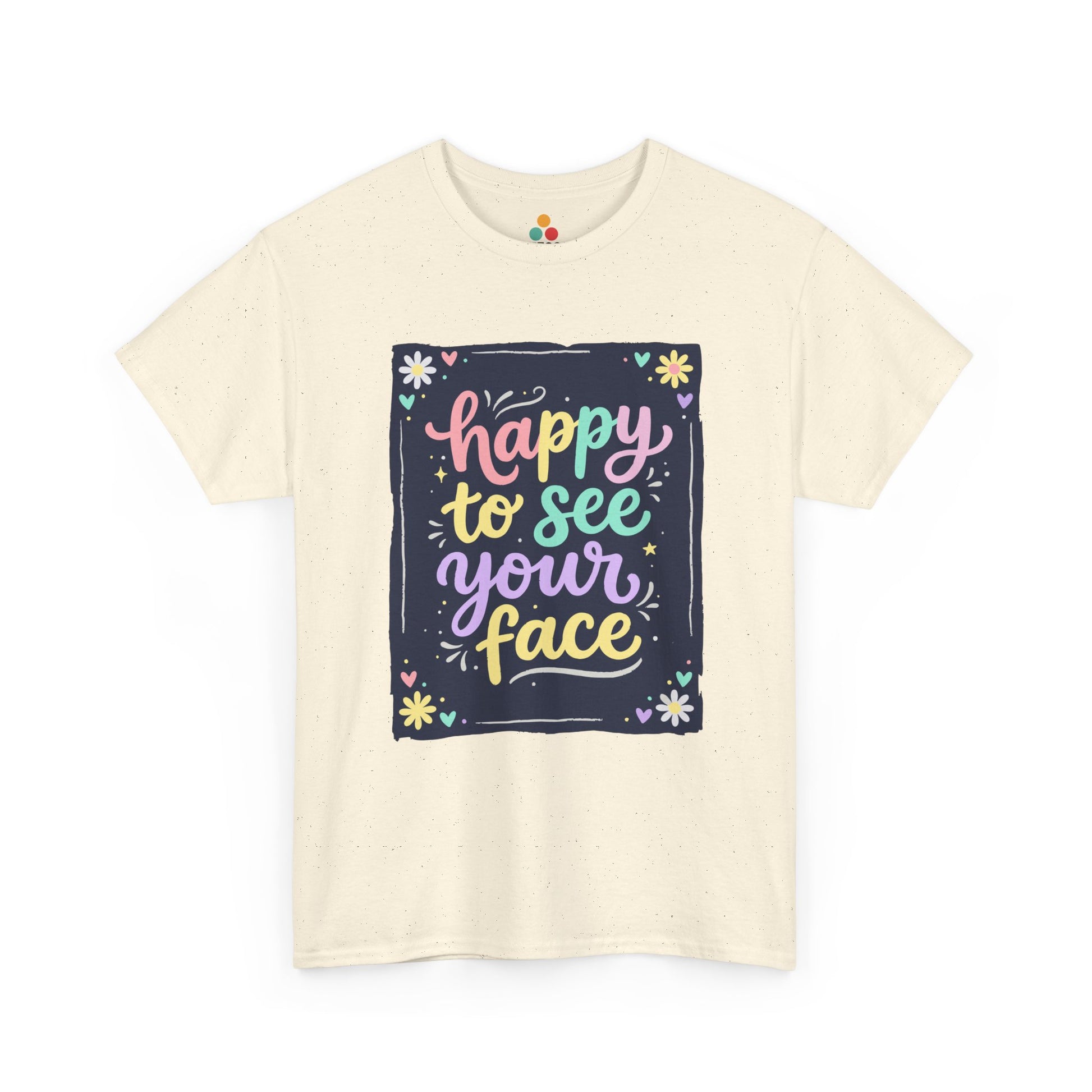 Close-up of a Light BEIGE T-shirt featuring a colorful "Happy to See Your Face" hand-lettered graphic framed with flowers and hearts on a navy background panel.
