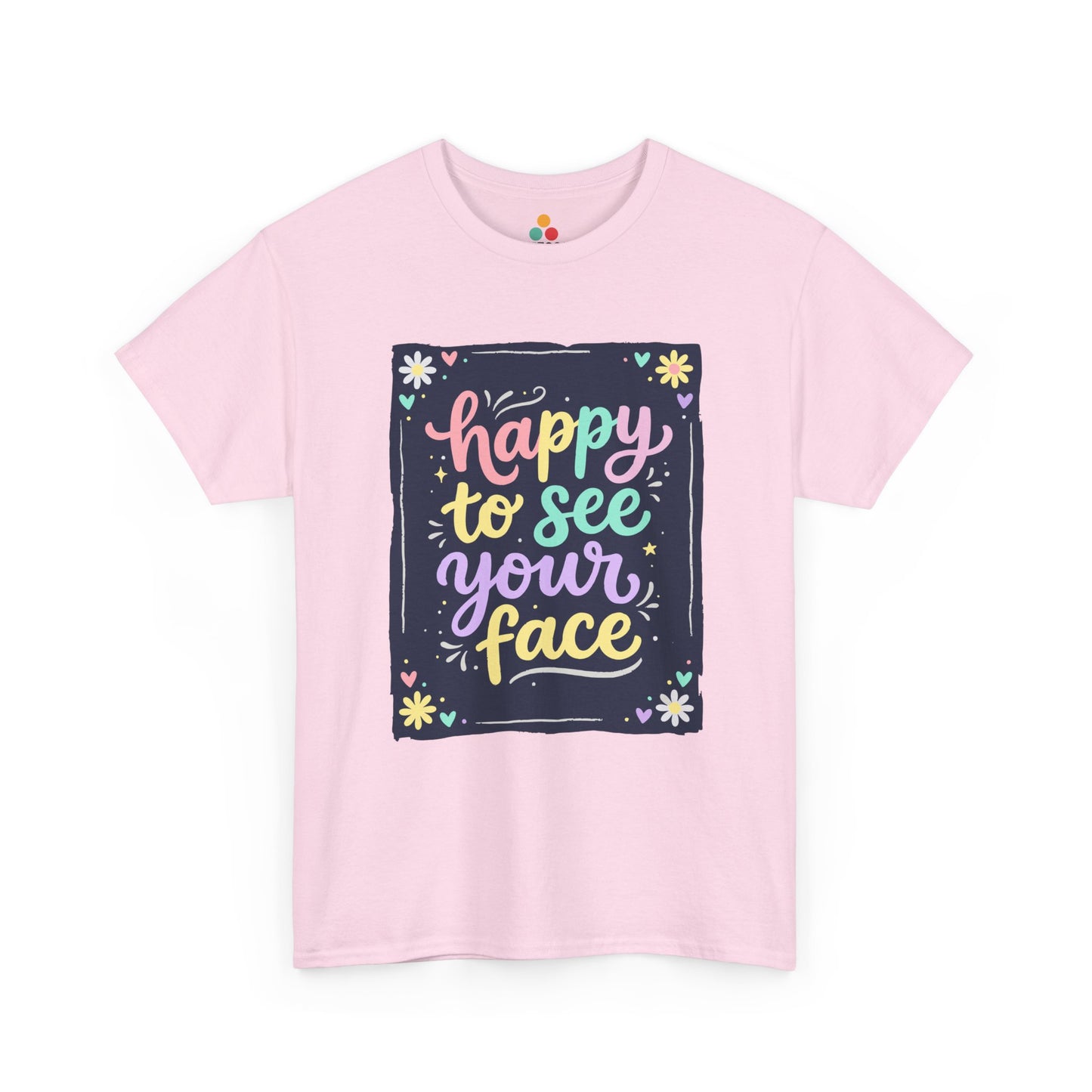 Close-up of a Light Pink T-shirt featuring a colorful "Happy to See Your Face" hand-lettered graphic framed with flowers and hearts on a navy background panel.
