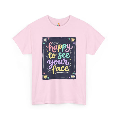 Close-up of a Light Pink T-shirt featuring a colorful "Happy to See Your Face" hand-lettered graphic framed with flowers and hearts on a navy background panel.
