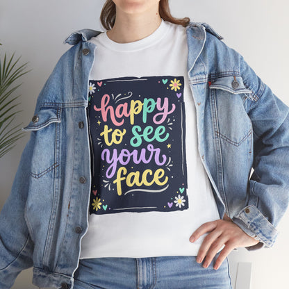 Close-up of a Women wearing white T-shirt featuring a colorful "Happy to See Your Face" hand-lettered graphic framed with flowers and hearts on a navy background panel.
