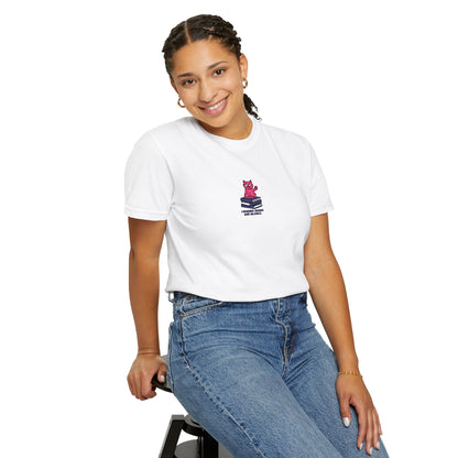   Close-up of a female model wearing Comfort Colors®  white shirt featuring an embroidered pink cat sitting on books with the saying “I Require Books and Silence.”

