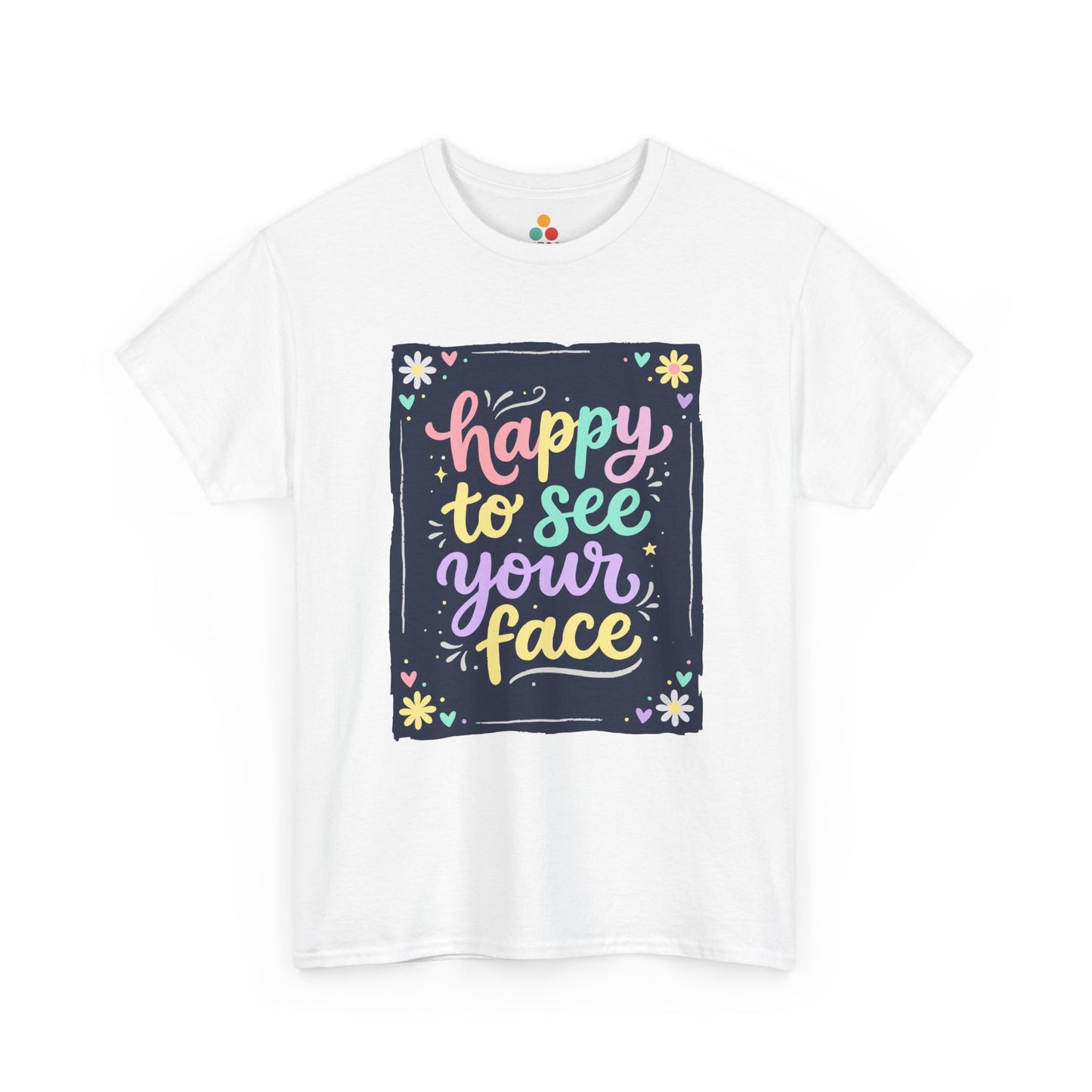 Close-up of a white T-shirt featuring a colorful "Happy to See Your Face" hand-lettered graphic framed with flowers and hearts on a navy background panel.
