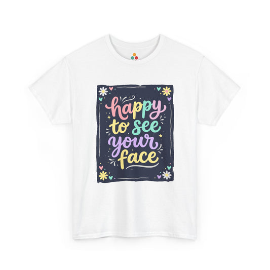 Close-up of a white T-shirt featuring a colorful "Happy to See Your Face" hand-lettered graphic framed with flowers and hearts on a navy background panel.

