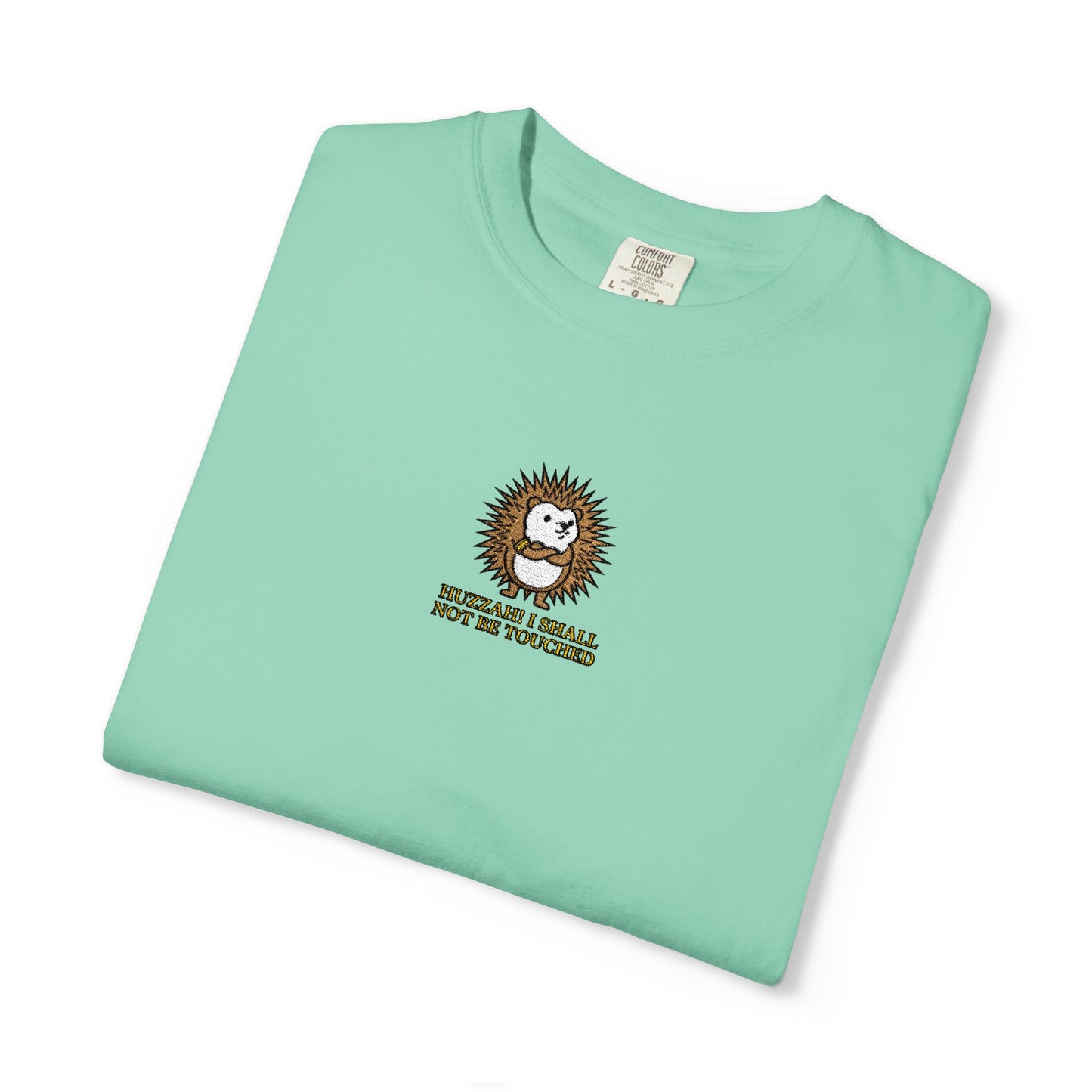 Close-up of an Island Reef Comfort Colors® shirt featuring an embroidered hedgehog in a defensive curl with the saying "Huzzah! I Shall Not Be Touched."

