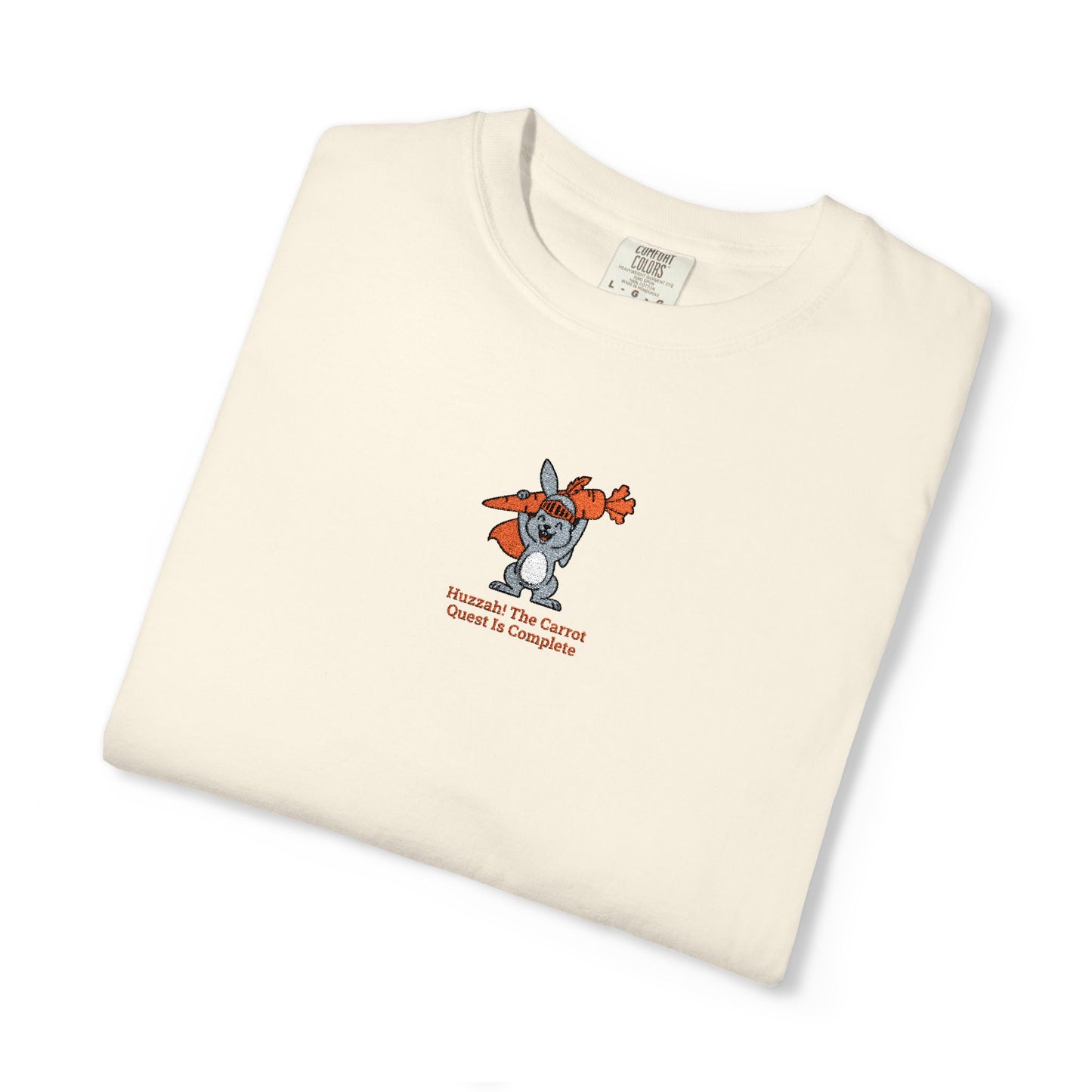 Close-up of a Comfort Colors® shirt featuring a rabbit holding carrots with the saying “Huzzah! The Carrot Quest Is Complete.”

