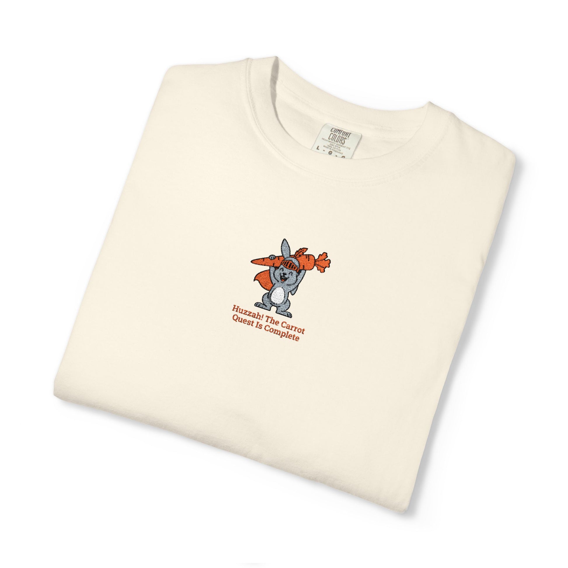 Close-up of a Comfort Colors® shirt featuring a rabbit holding carrots with the saying “Huzzah! The Carrot Quest Is Complete.”

