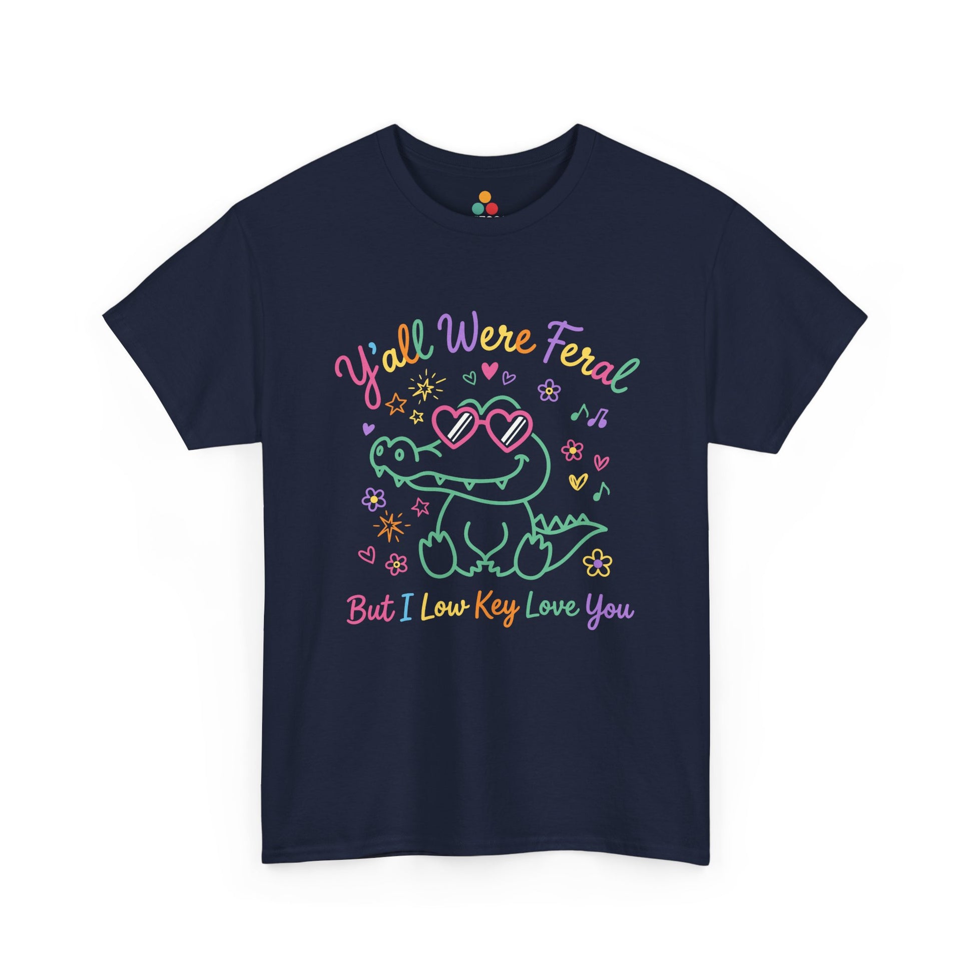 Front view of TEEZOCA navy T-shirt featuring a cute neon crocodile wearing heart-shaped sunglasses surrounded by colorful stars and flowers, with rainbow text reading "Y'all Were Feral But I Low Key Love You" — a funny last day of school teacher gift shirt.

