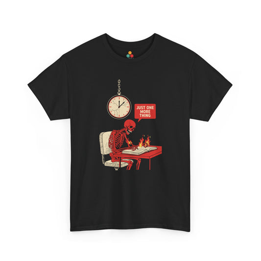 Graphic t‑shirt featuring a red skeleton sitting at a desk with hands on fire, writing in a book under a wall clock, with a speech bubble saying “Just One More Thing.”
