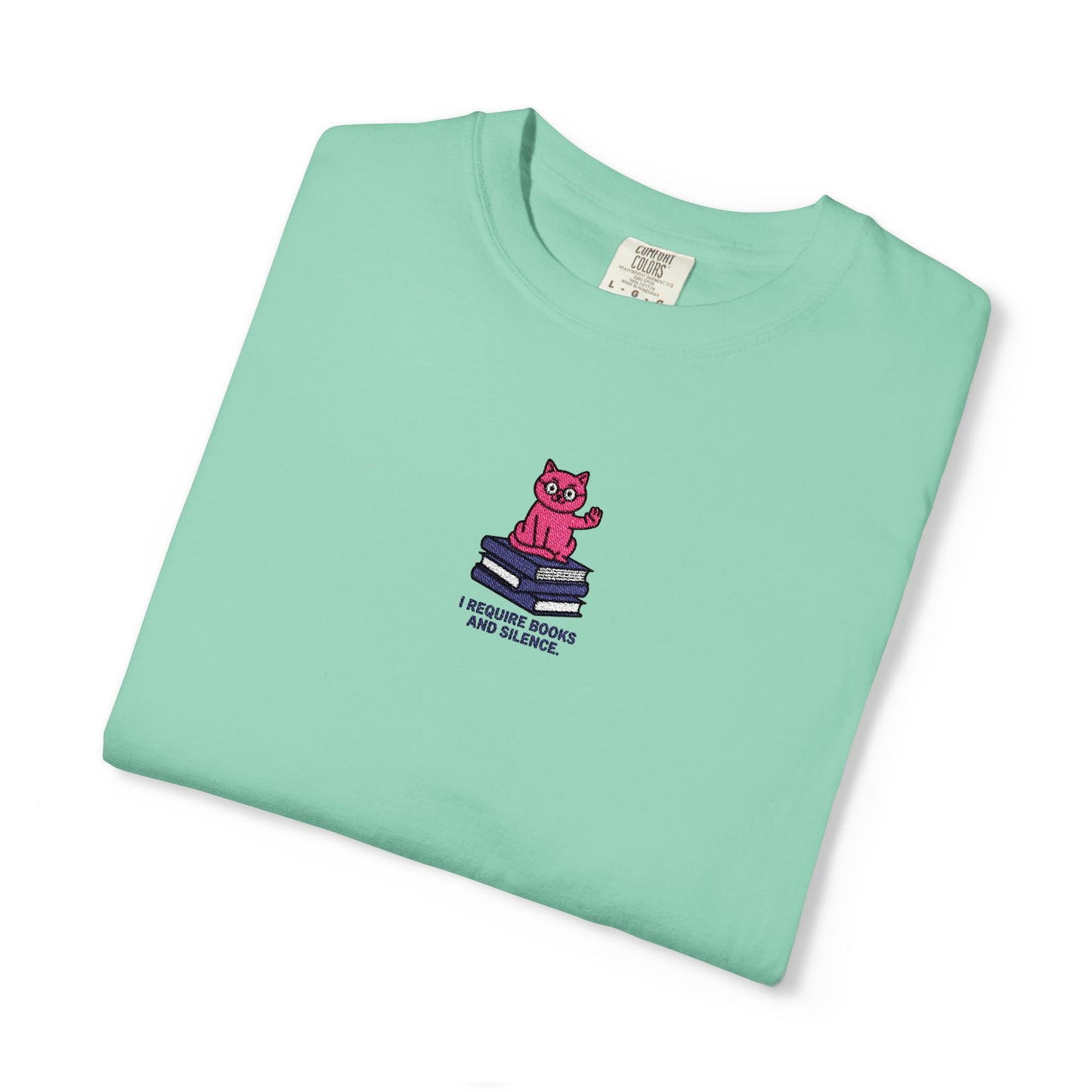  Island reef  Close-up of a Comfort Colors®  Ishirt featuring an embroidered pink cat sitting on books with the saying “I Require Books and Silence.”
