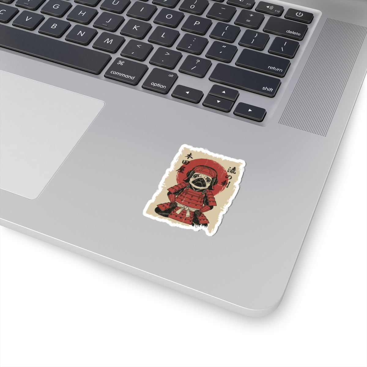Laptop with a sticker of a dog in a red outfit on a white surface