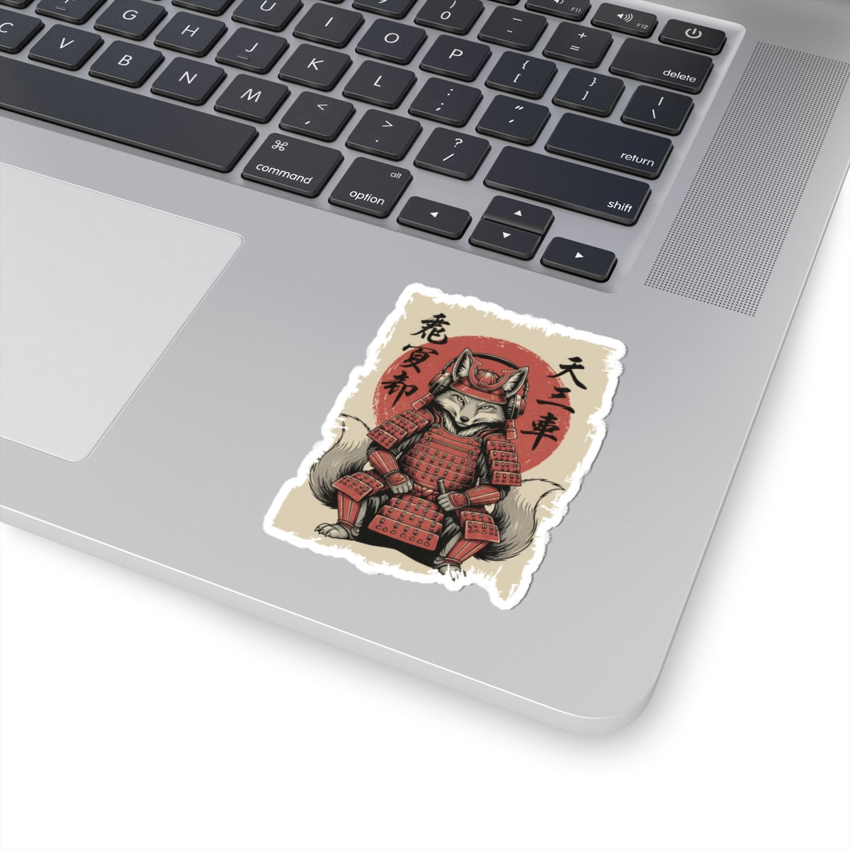 Laptop with a sticker of a fox in samurai armor on a white surface