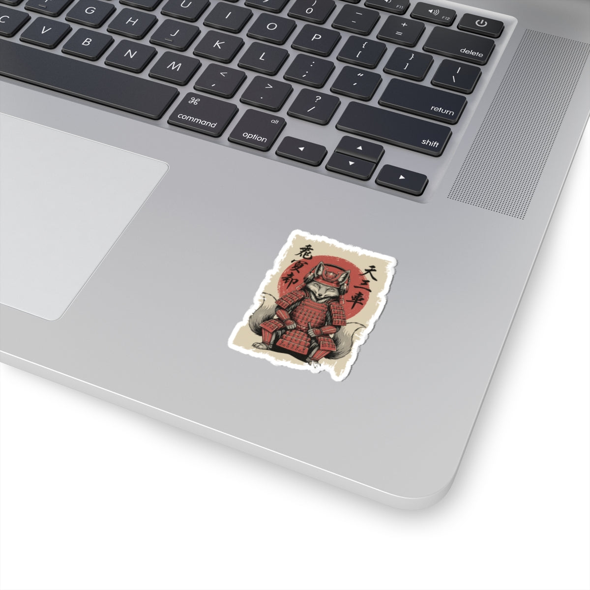 Laptop with a sticker of a fox in samurai armor on the palm rest area.