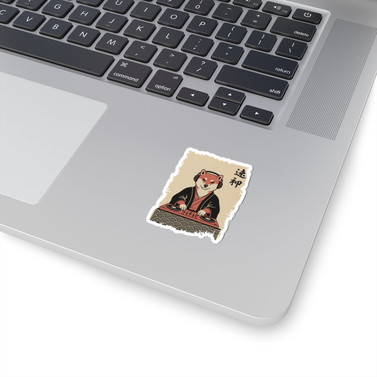 Laptop with a sticker of a fox in traditional Japanese attire on a white surface