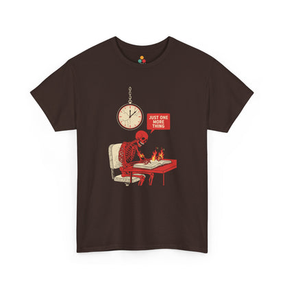 Maroon t‑shirt featuring a red skeleton sitting at a desk with hands on fire, writing in a book under a wall clock, with a speech bubble saying “Just One More Thing.”
