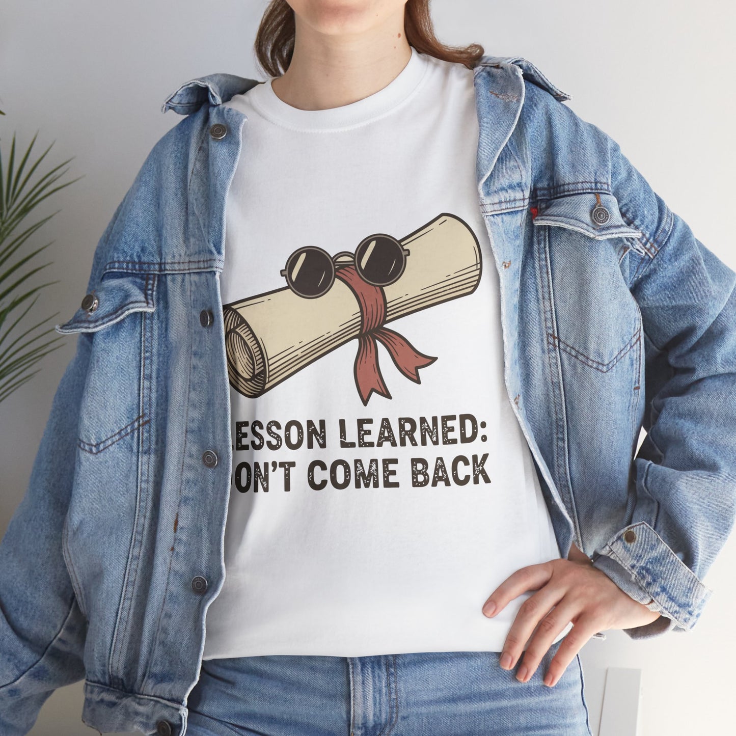 Model with denim jacket wearing TEEZOCA Lesson Learned T-Shirt with vintage scroll illustration in white.