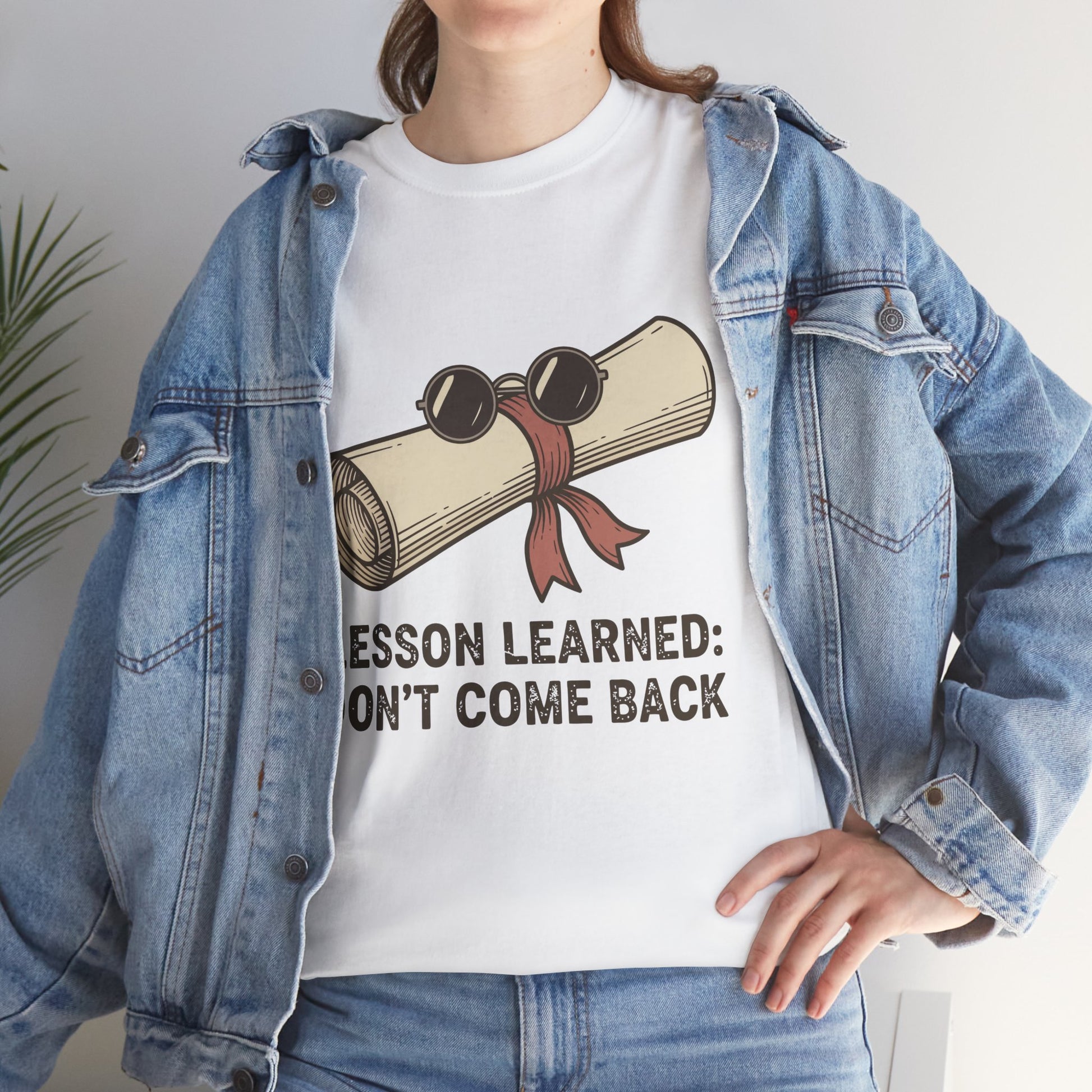 Model with denim jacket wearing TEEZOCA Lesson Learned T-Shirt with vintage scroll illustration in white.